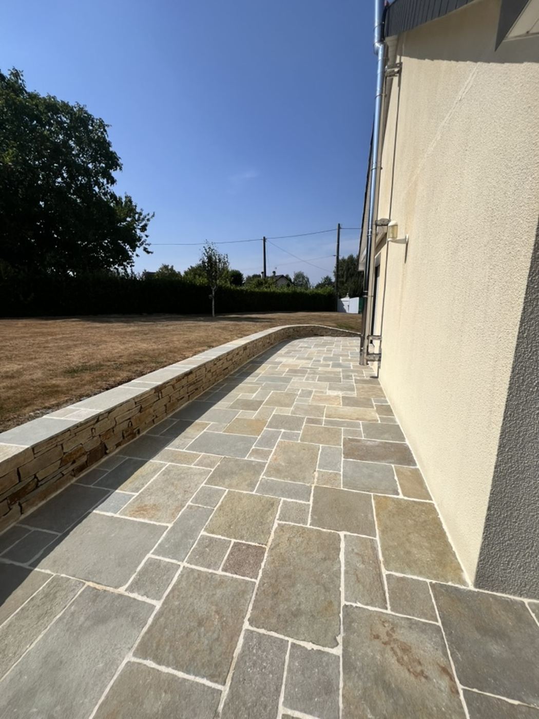 Aménagement extérieur par Nouvel Espace — allée dallée le long de la façade